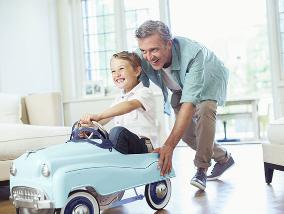 Grandfather pushing young grandson with toy car